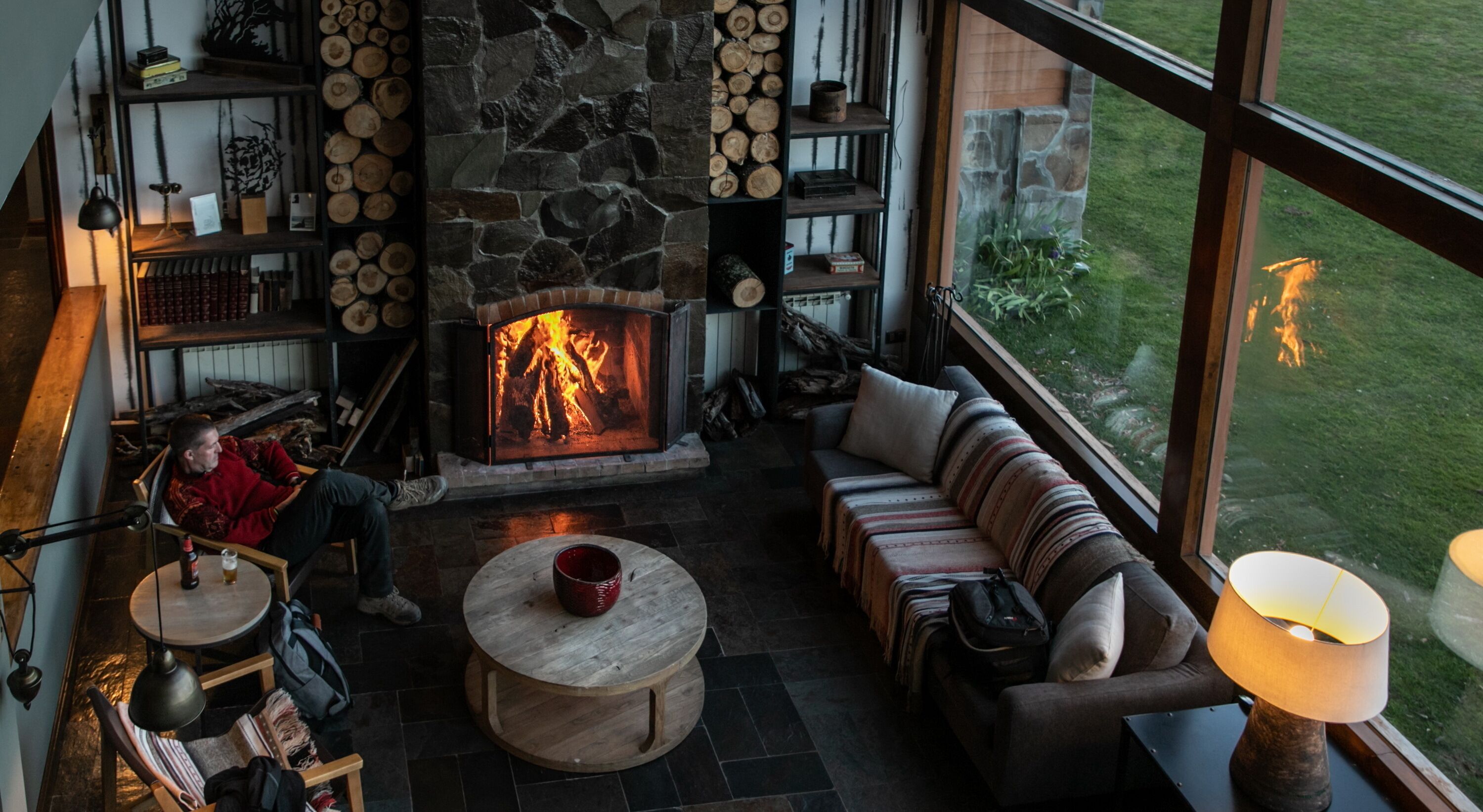 Una sala de estar acogedora con chimenea de piedra, un sofá y vistas al exterior.