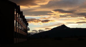 Un edificio con balcón que da a un paisaje montañoso al atardecer.