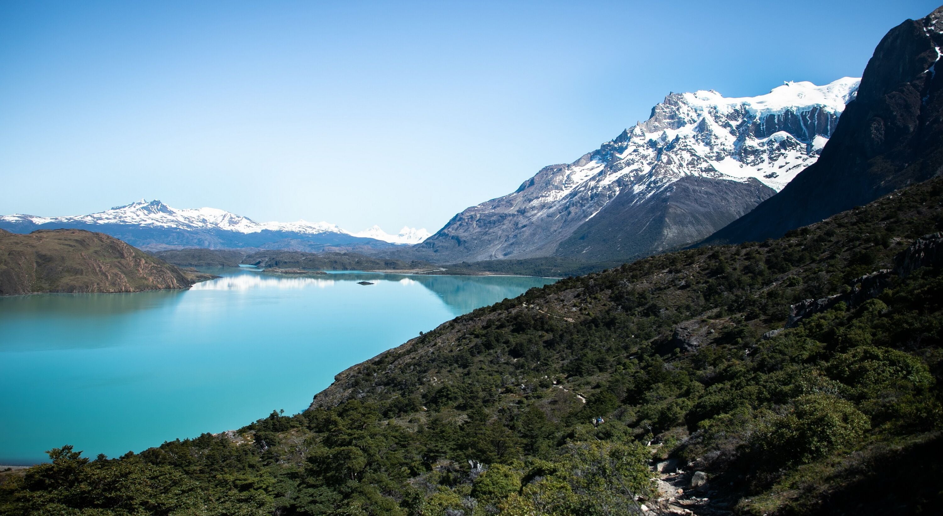 A mountainous landscape with a lake and snow-capped peaks.
