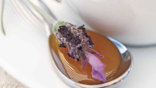 A spoon with a dried flower and a cup of tea.
