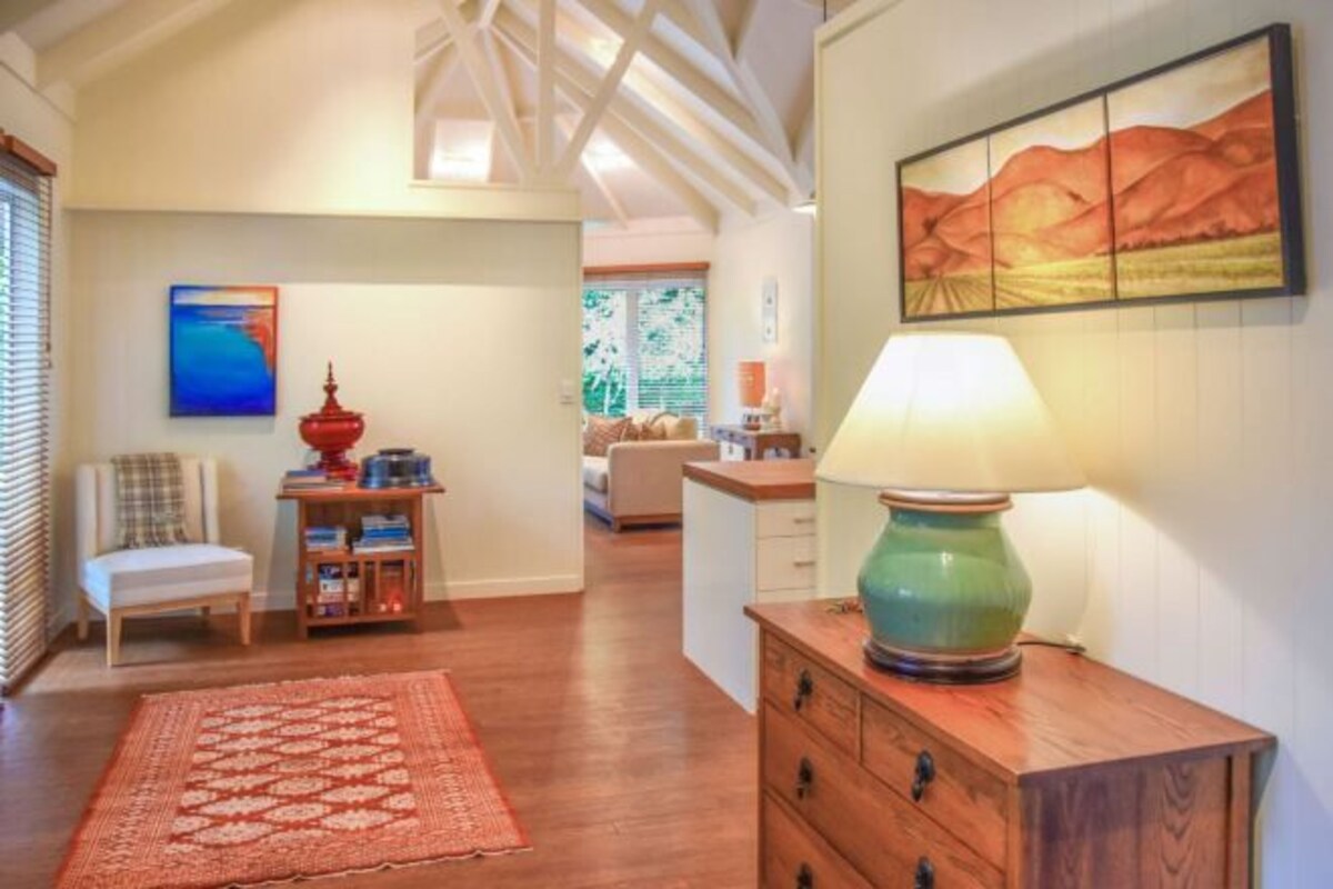 A living room with a wooden floor, a red patterned rug, a wooden cabinet, and a painting on the wall.