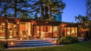 A modern house with a large porch, outdoor seating, and a well-maintained garden.