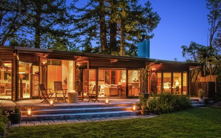 A modern house with a large porch, outdoor seating, and a well-maintained garden.