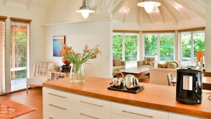 A modern kitchen with a wooden countertop, a coffee machine, and a vase with flowers. - River Birches (Turangi)