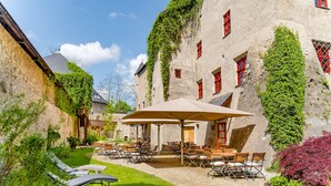 Une cour avec des espaces de repos en plein air, des bâtiments en pierre et de la verdure.