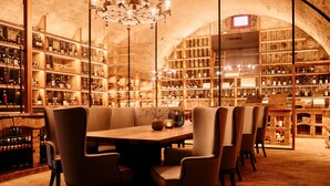 Une cave à vin avec une table ronde et des chaises, entourée d’étagères remplies de bouteilles de vin.