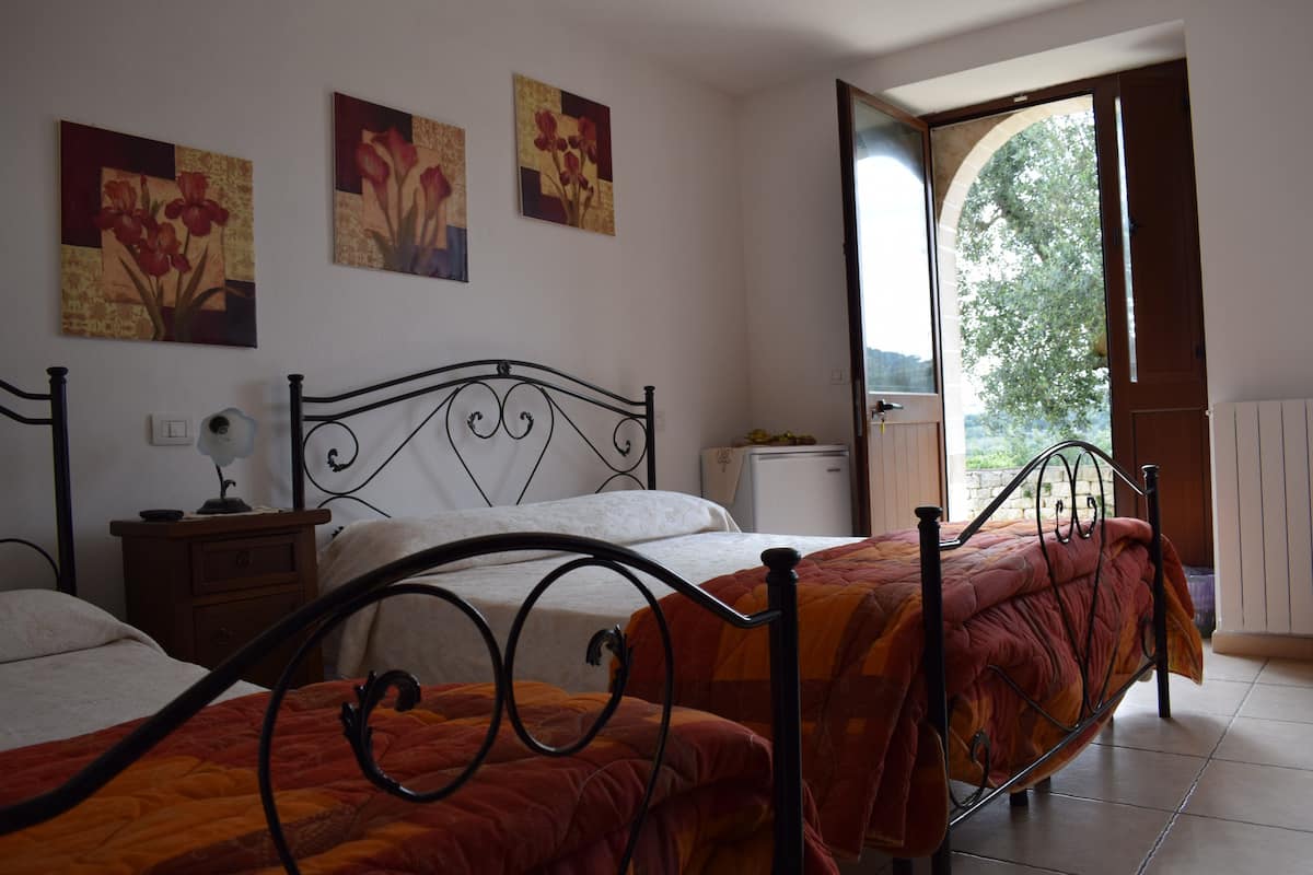 Ein Schlafzimmer mit zwei Betten, einem Nachttisch, einer Kommode und einer Tür, die auf einen Balkon führt.