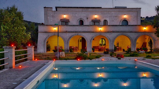 A building with a pool, featuring arched doorways and outdoor seating areas.