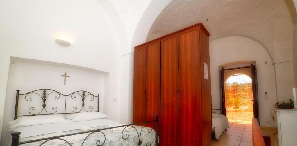 Quarto com cama, guarda-roupa e cruz na parede.
