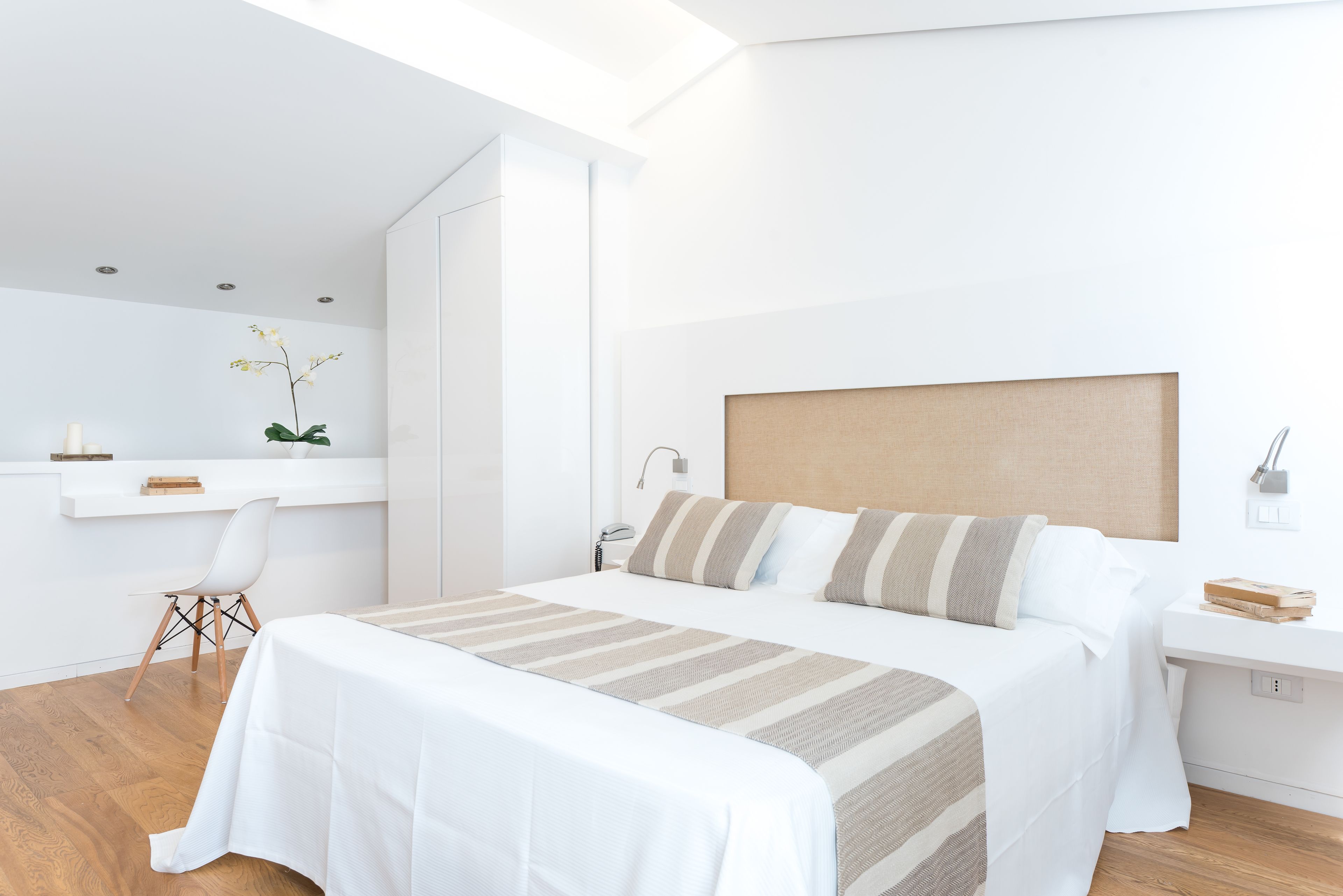 A modern hotel room with a large bed, a desk, and a chair.