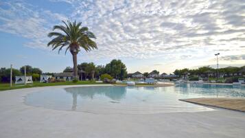 A large outdoor swimming pool with lounge chairs and palm trees.