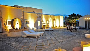 Un patio con suelo de piedra, sillones y una mesa con sillas.