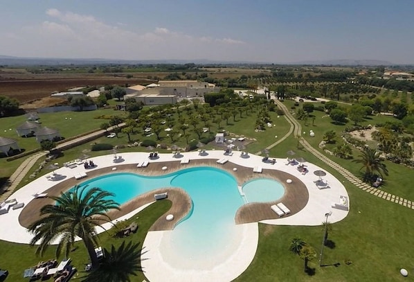 Relax by the resort's winding pool, surrounded by lush greenery and expansive countryside views.