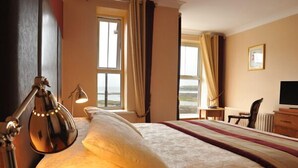 Camera d'albergo con un letto, una scrivania, una lampada e vista sull'esterno.