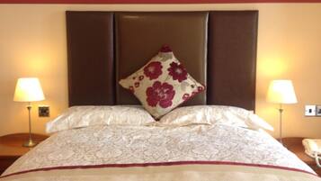 A neatly made bed with a floral pillow, two bedside lamps, and a telephone on the nightstand.