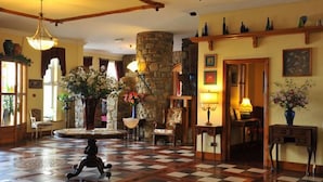 Una hall con pavimento a scacchi, una colonna in pietra e un lampadario.