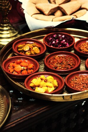 A tray with various dishes, including a bowl of sliced carrots, a bowl of red cabbage, and a bowl of yellow fruit. - La Maison Bleue Batha (Fes)