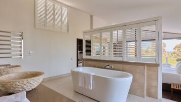 A modern bathroom with a freestanding bathtub, two stone bowls, and a large mirror.