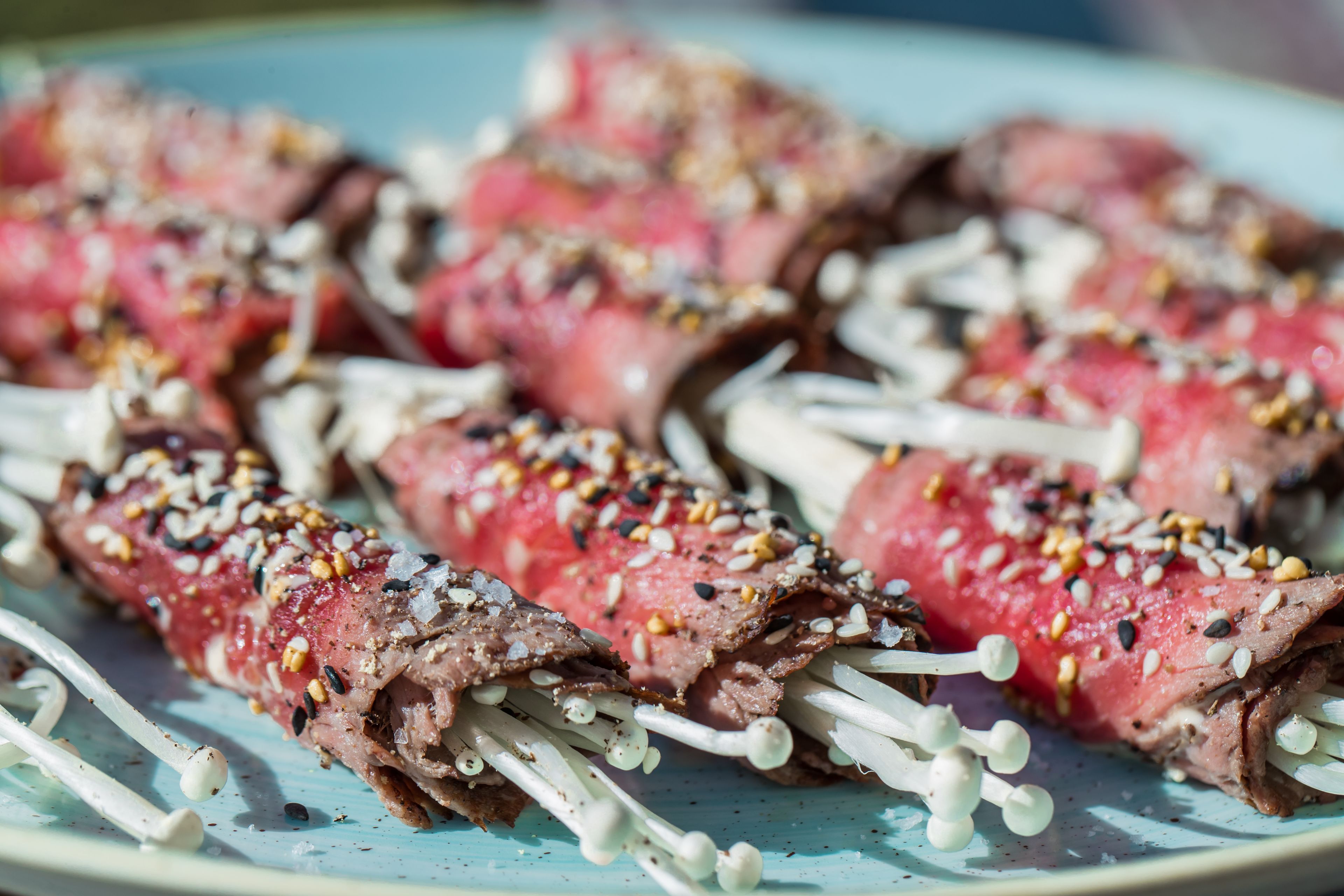 Skewers of meat with sesame seeds and mushrooms on a plate.