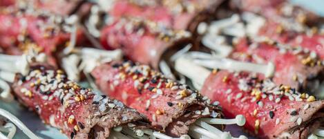 Skewers of meat with sesame seeds and mushrooms on a plate.