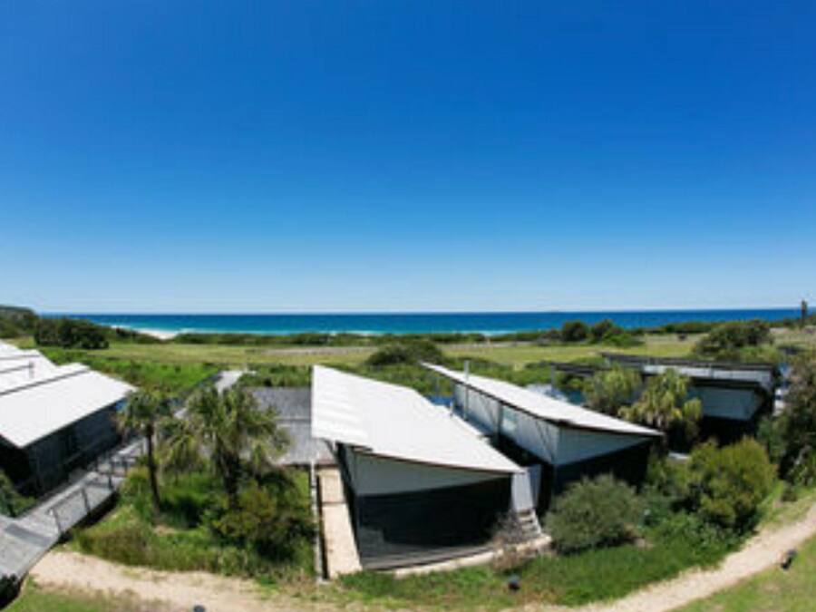 A series of modern, white-roofed buildings with a clear view of the ocean in the background.