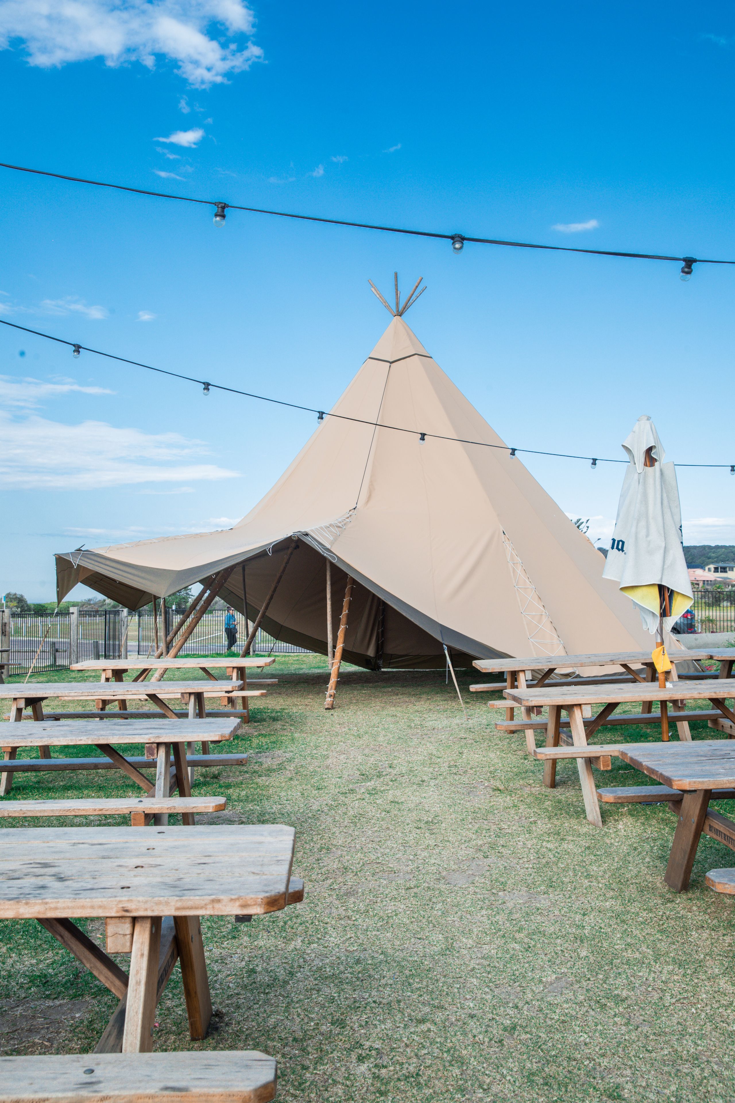 A large teepee-style tent with picnic tables arranged in front.