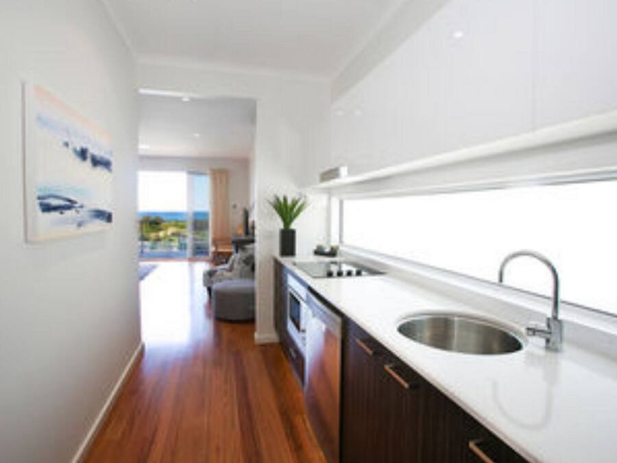 Una cocina moderna con un ventanal grande, suelo de madera y vistas al exterior.