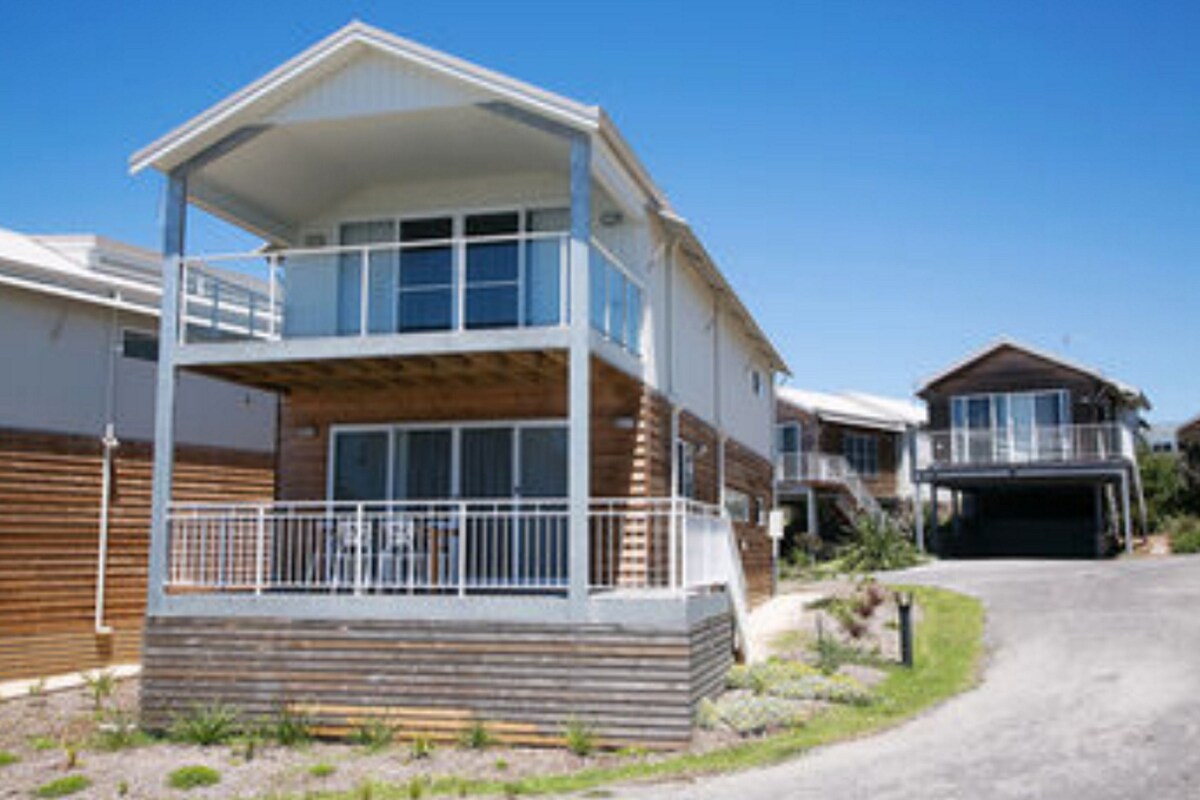 Une maison à deux étages avec un balcon, un garage et une allée.