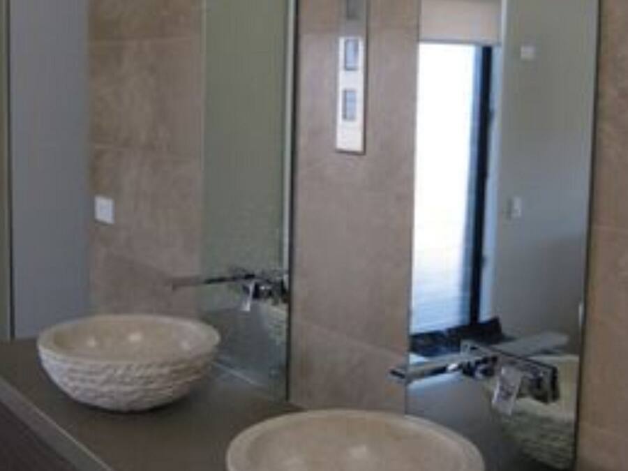 A bathroom with two stone bowls as sinks, a large mirror, and a door in the background.