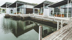 Une propriété située au bord de l’eau, comprenant plusieurs chalets modernes, chacun doté d’un balcon et offrant une vue sur l’eau.