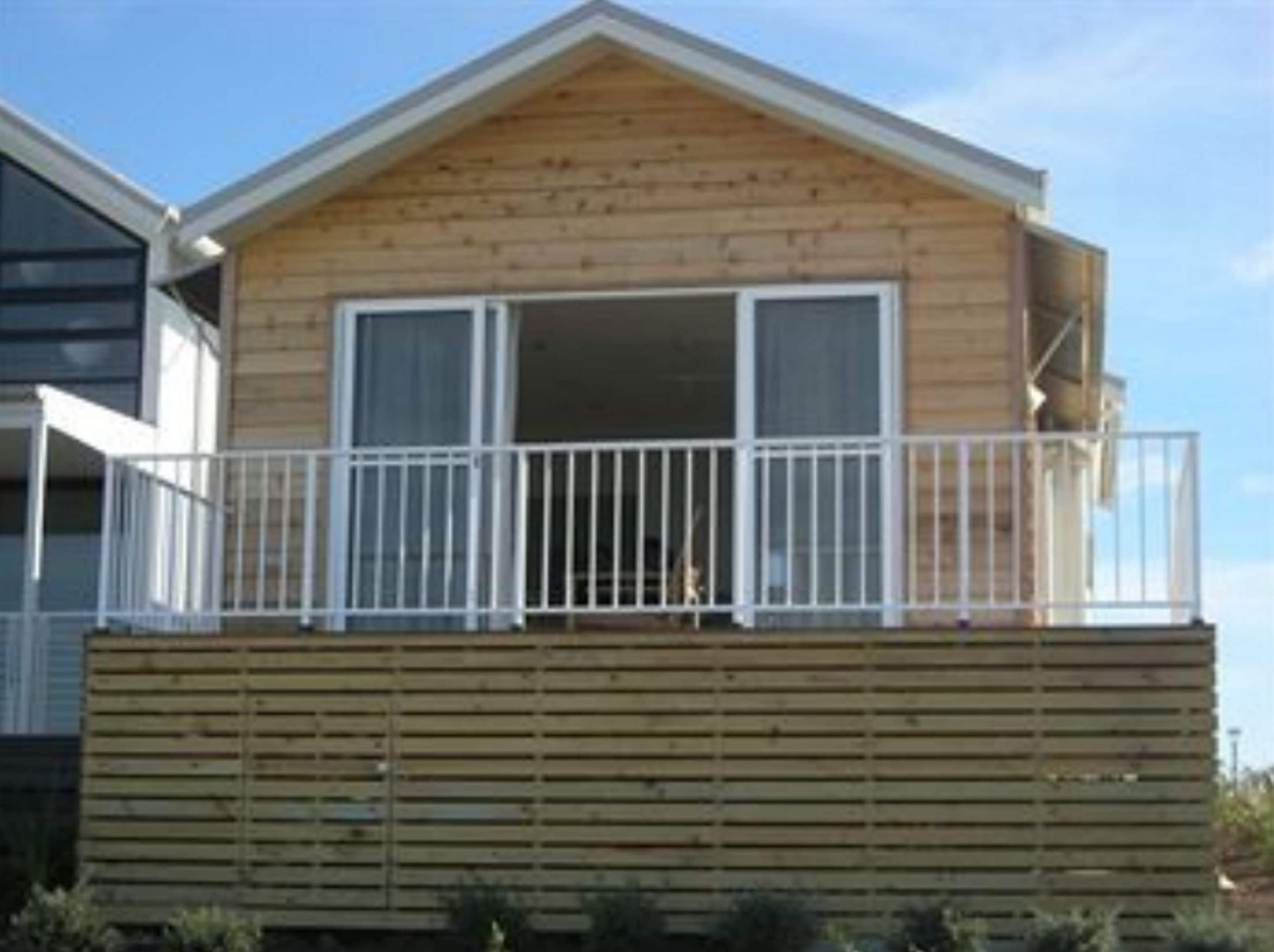 A wooden cabin with a balcony and large windows.