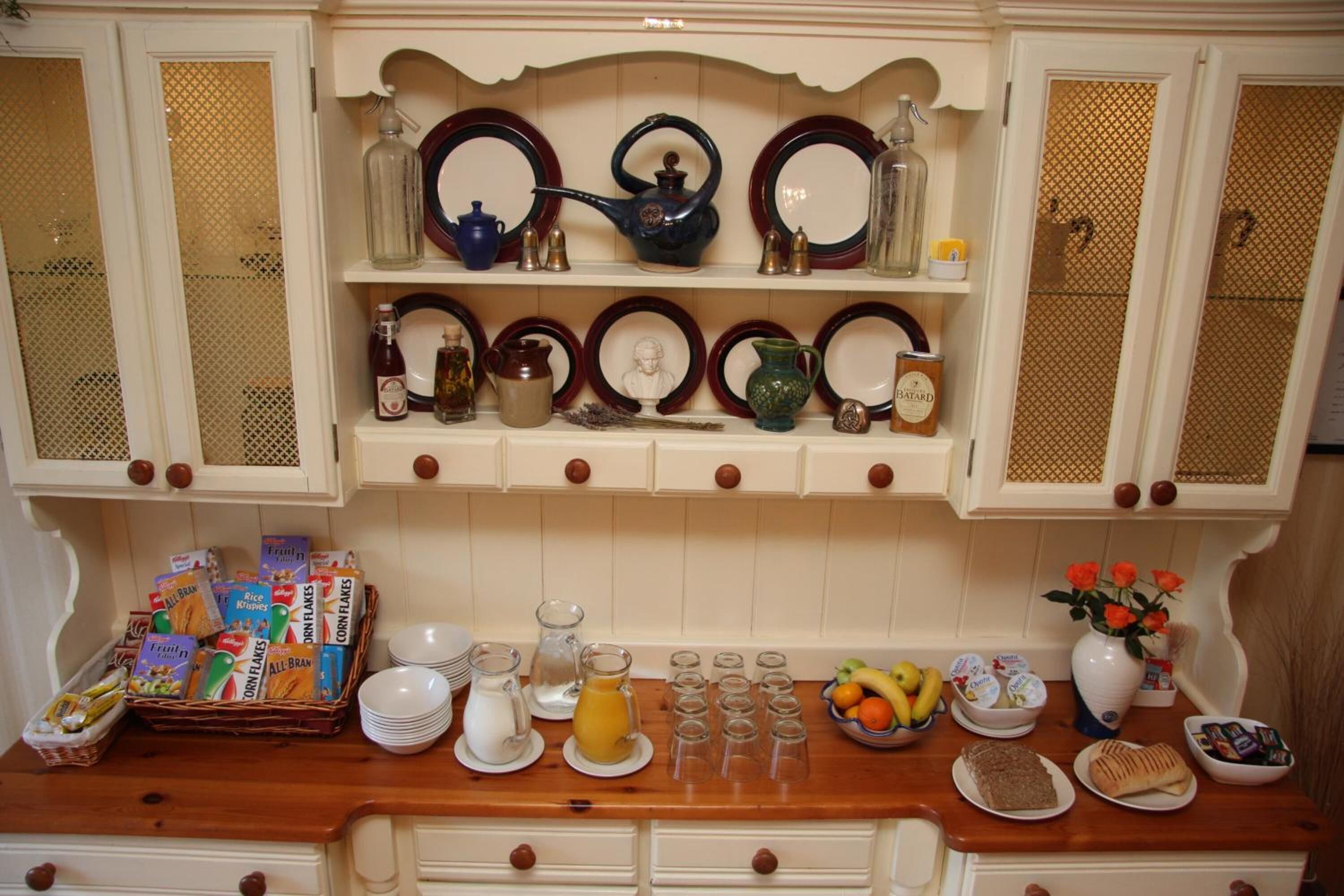 A kitchen with white cabinets, a wooden countertop, and various kitchenware including plates, bowls, and a fruit basket.