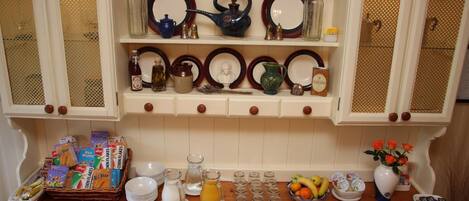 A kitchen with white cabinets, a wooden countertop, and various kitchenware including plates, bowls, and a fruit basket.
