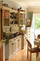 A kitchen with wooden cabinets, a dining table, and a window with a view of greenery.