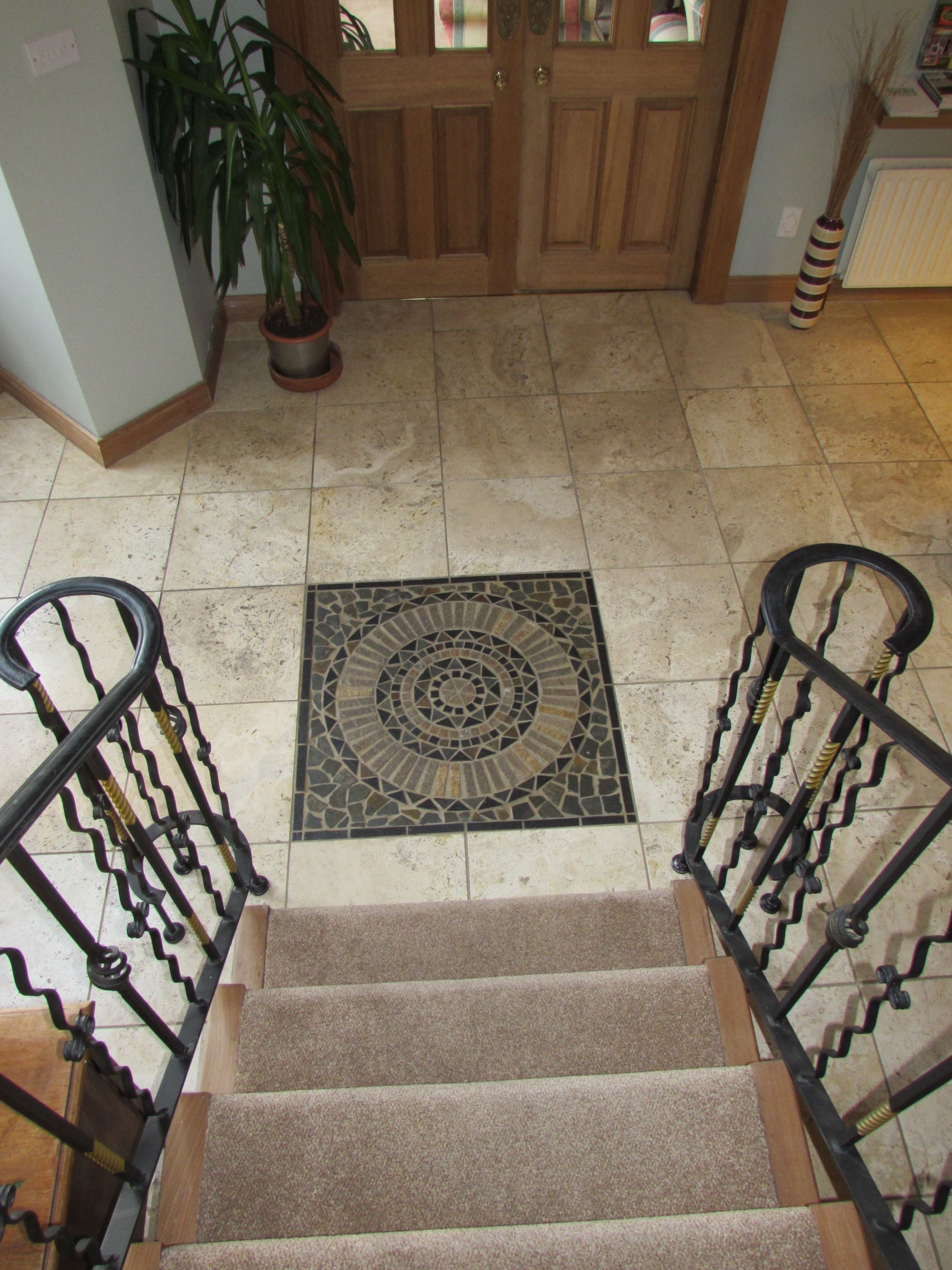 Una escalera con un felpudo estampado, una planta en maceta y una puerta de madera con paneles de vidrio.