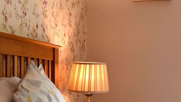 Una cama bien hecha con almohadas, cabecera de madera, lámpara y un cuadro en la pared.