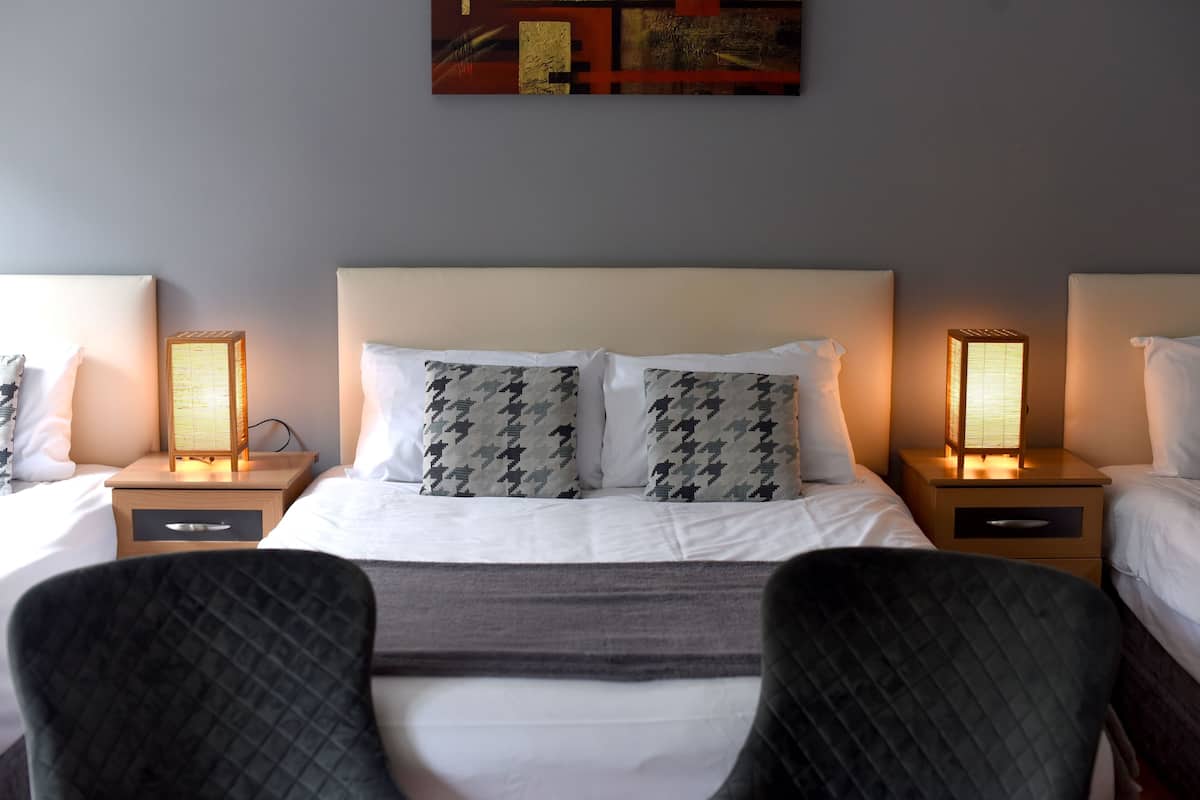 Una habitación de hotel con una cama grande, dos mesitas de noche con lámparas y un cabecero.