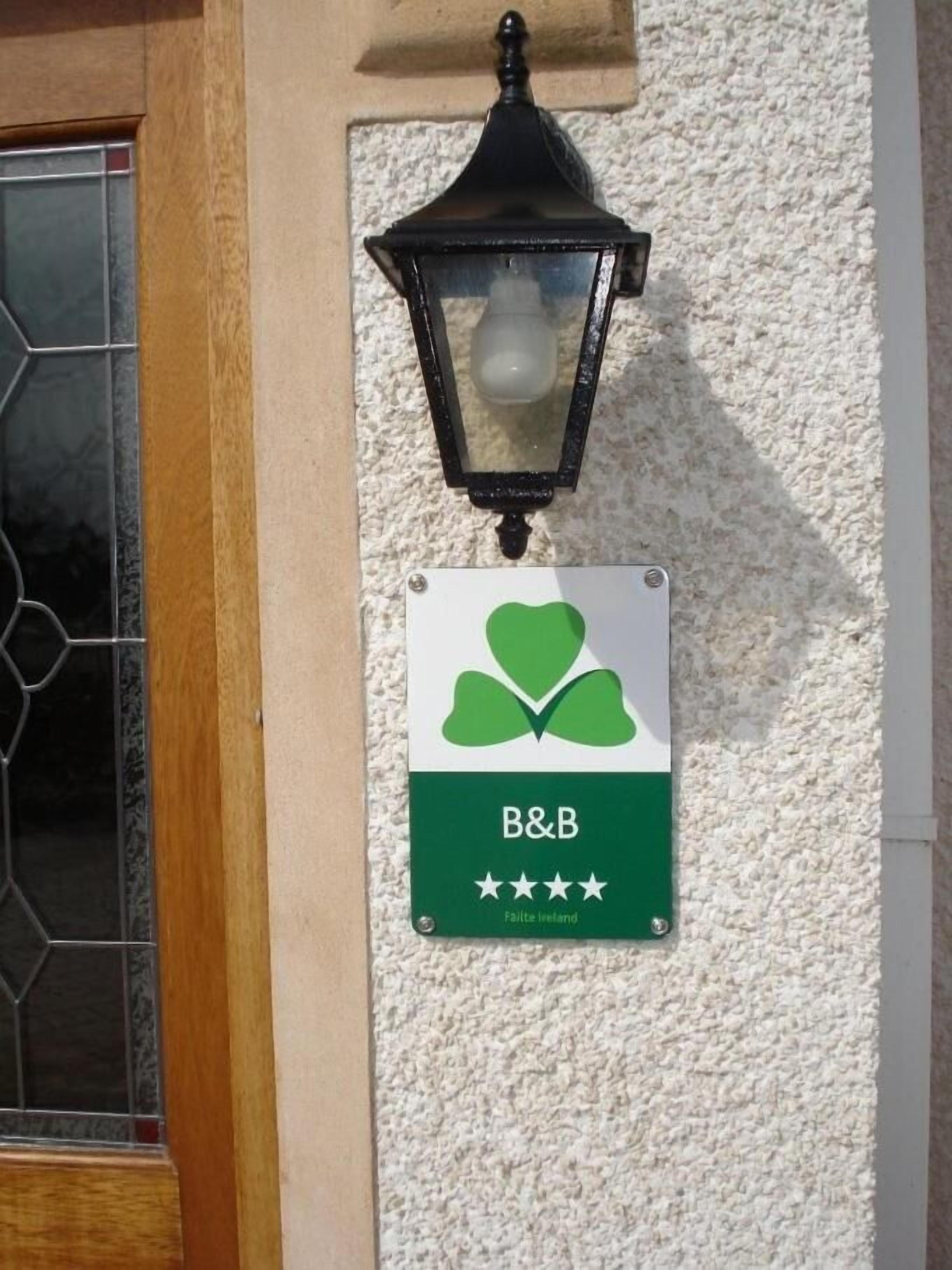 A B&B sign with a four-star rating, mounted on a textured wall above a wooden door.