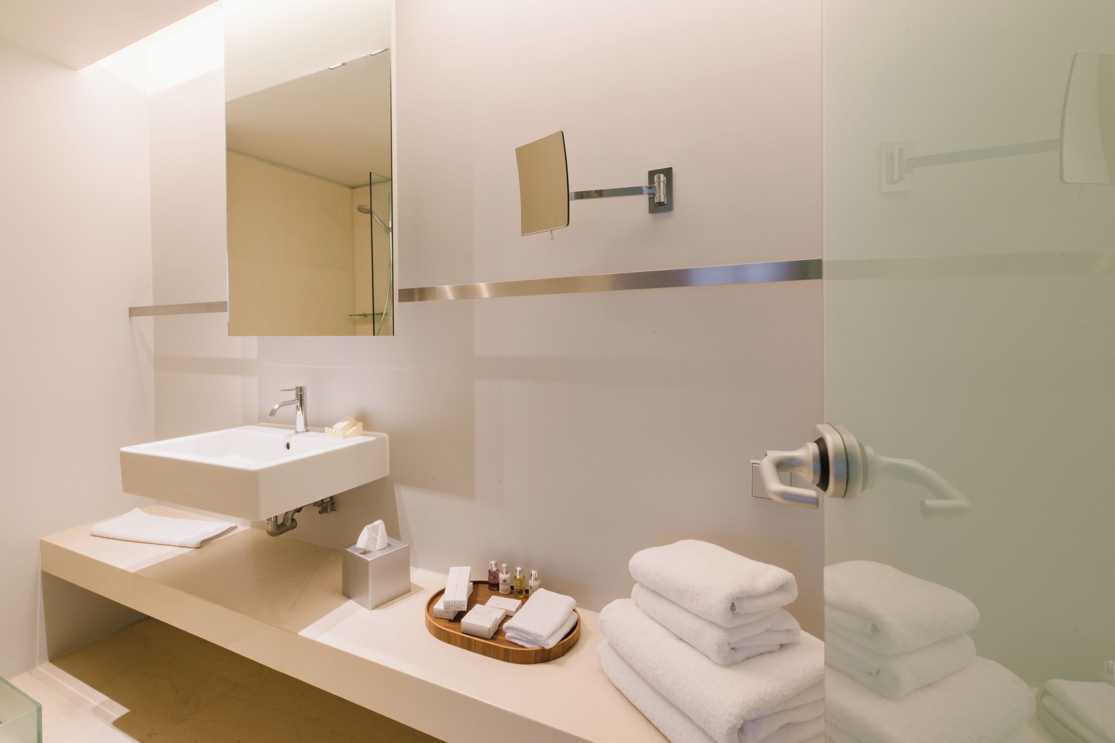 Un baño moderno con un espejo grande, un lavamanos y una cabina de ducha de vidrio.