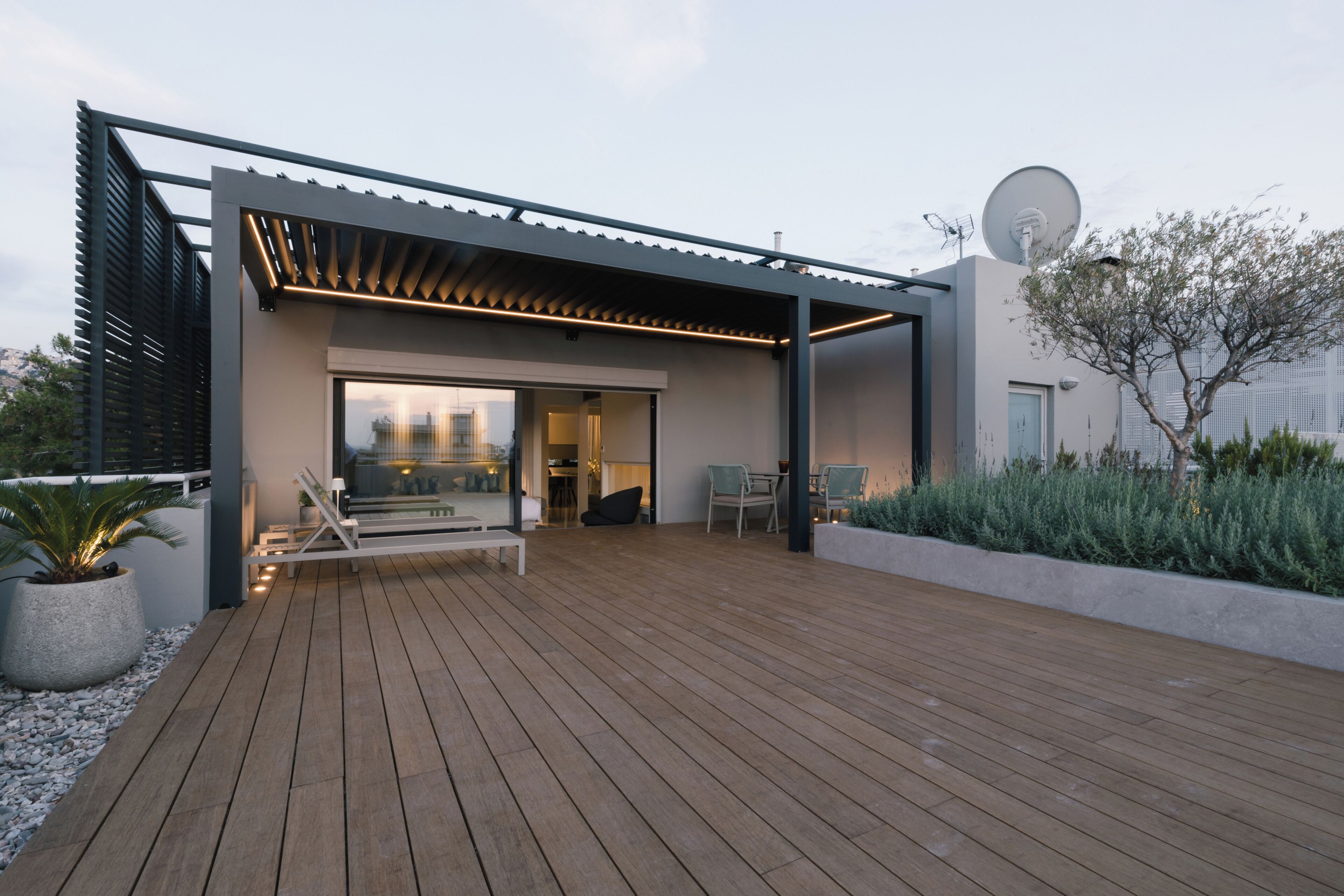 A modern outdoor patio with a pergola, seating area, and a view of the cityscape.