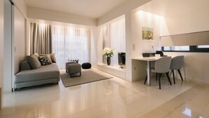 Ein modernes Wohnzimmer mit einer Couch, einem Essbereich mit Stühlen, einem kleinen Tisch und einem Fenster mit Vorhängen.