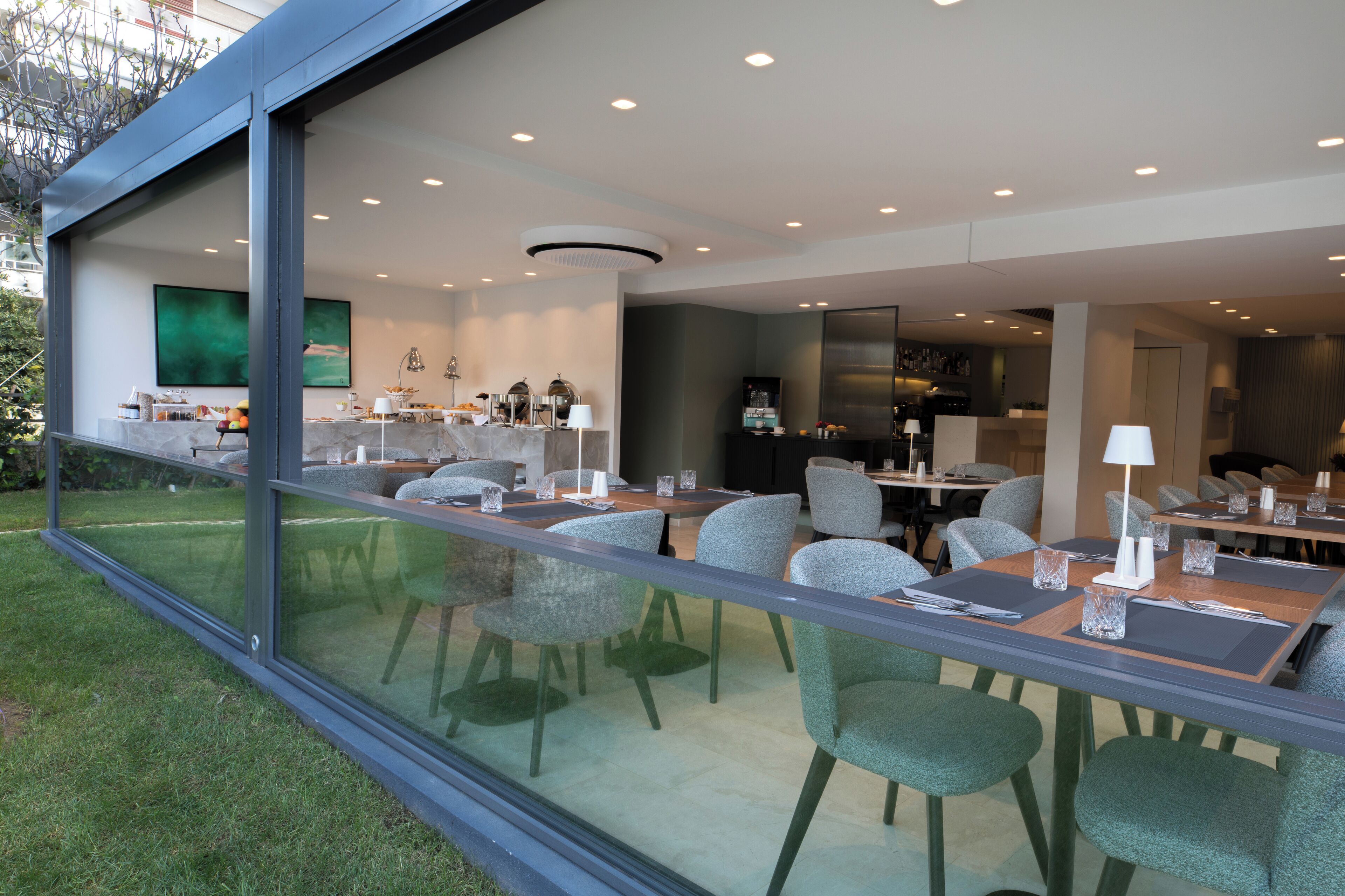 Un comedor moderno con paredes de vidrio, mobiliario contemporáneo y vistas al exterior.