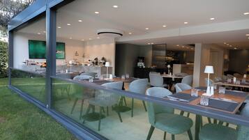 A modern dining area with glass walls, contemporary furniture, and a view of the outdoors.