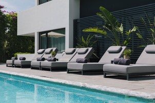 A poolside area with lounge chairs and a modern building in the background.