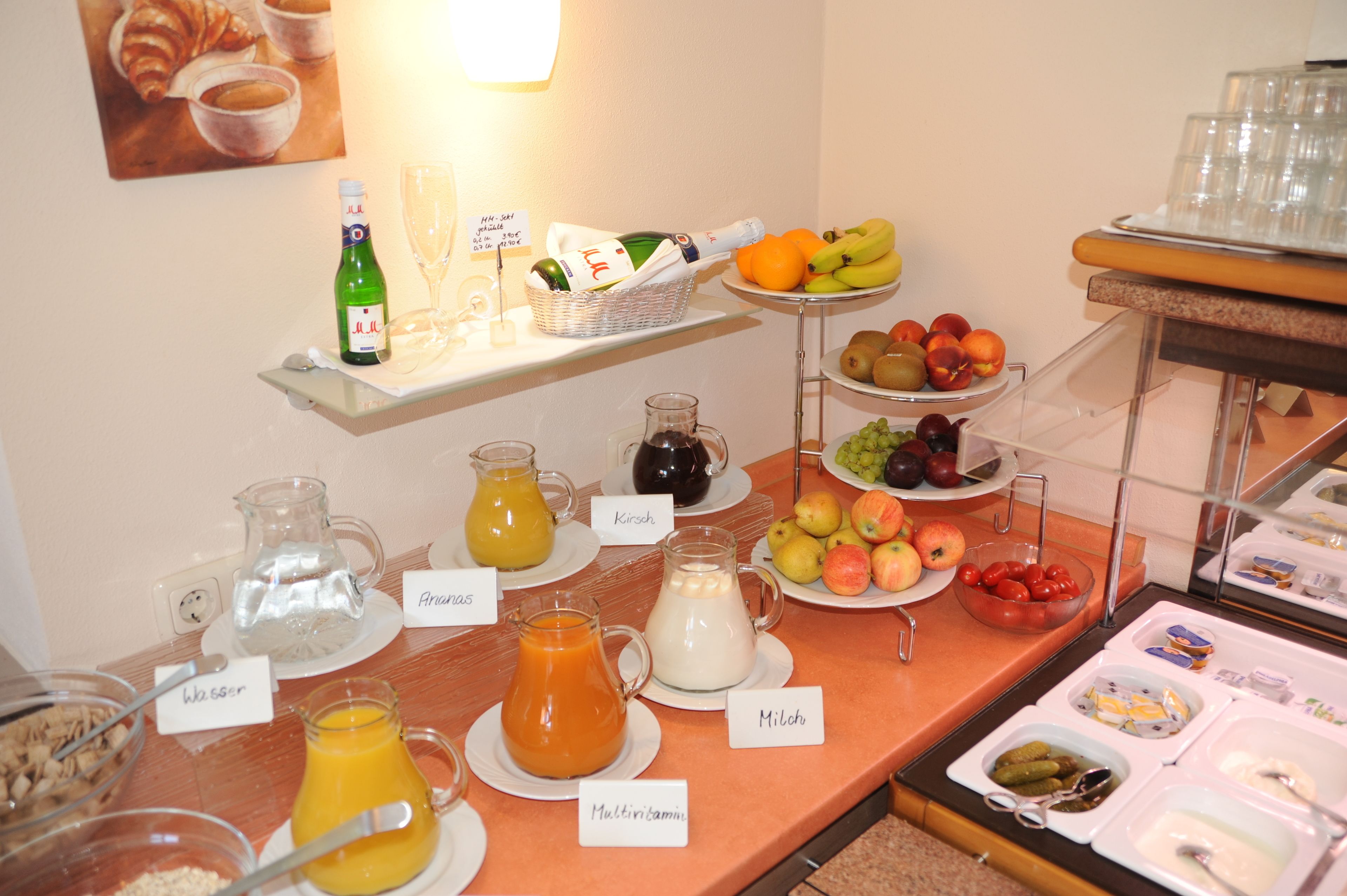 A breakfast buffet with various food and drink options, including fruits, juices, and dairy products.