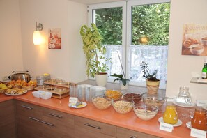 A breakfast buffet with various food items and a potted plant. - Hotel Post (Scheidegg)
