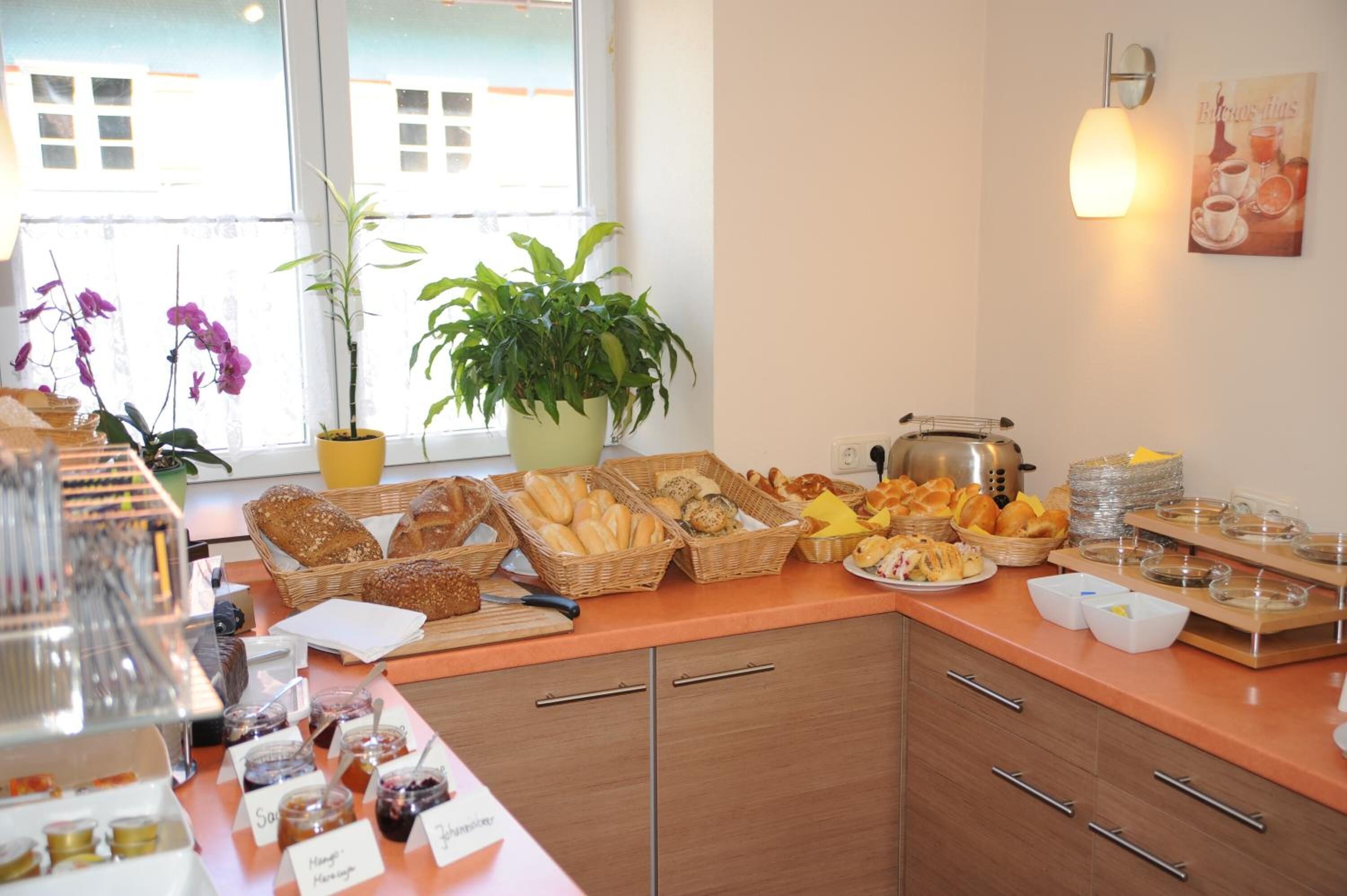 A breakfast buffet with various breads, pastries, and spreads.