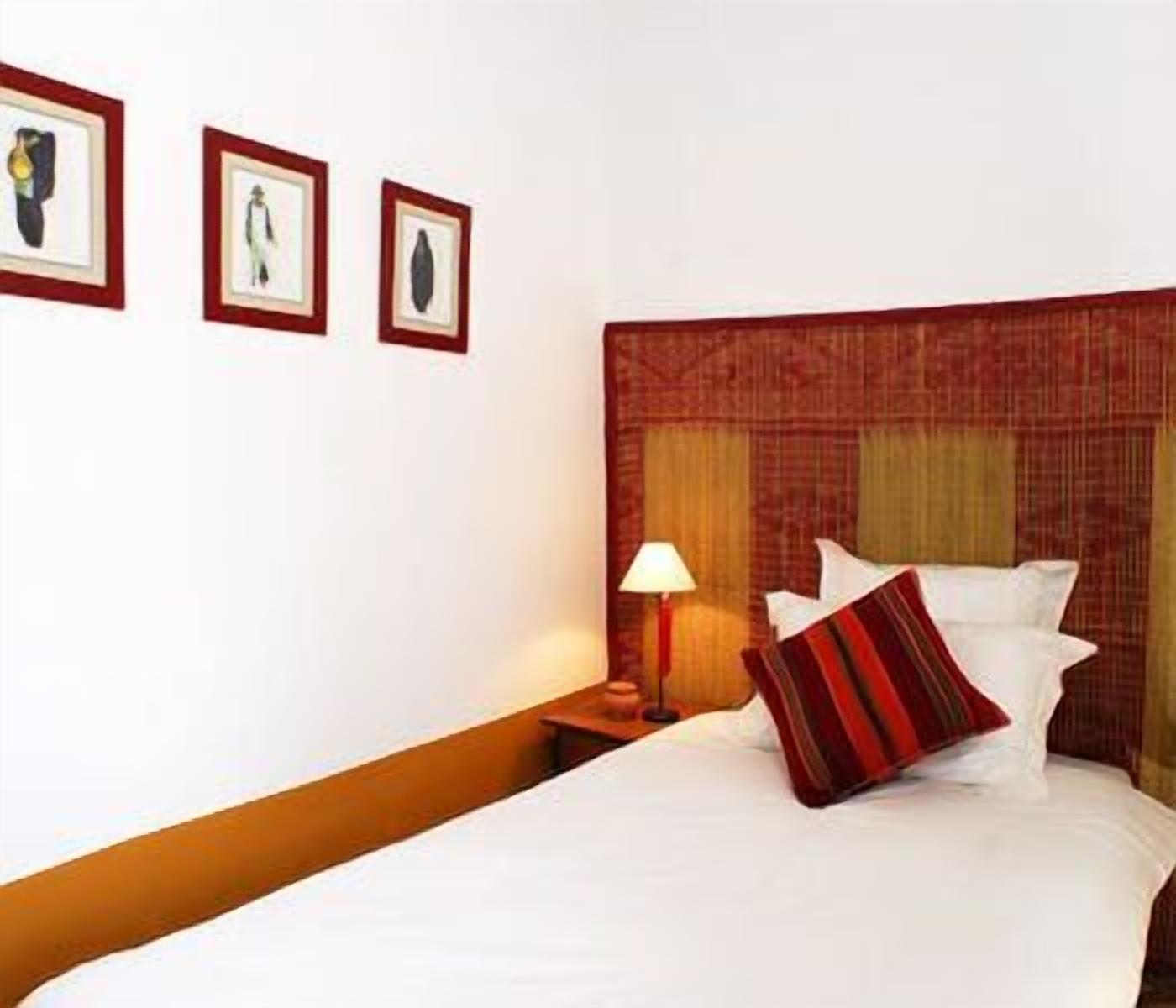 Une chambre d’hôtel avec un lit, une table de chevet, une lampe et trois tableaux encadrés accrochés au mur.