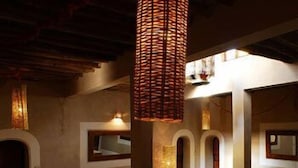 A staircase with a wooden railing and a woven light fixture above it. - Kasbah Dar Essalam (Skoura)