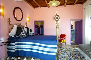 A bedroom with a bed, a chair, a lamp, and a door.